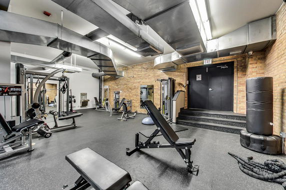 Indoor gym area with exercise equipment and brick walls.