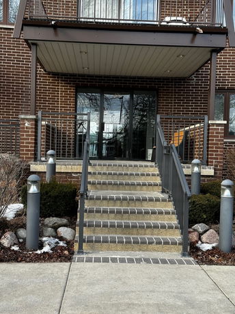 Front view of a building entrance with stairs and a glass door.
