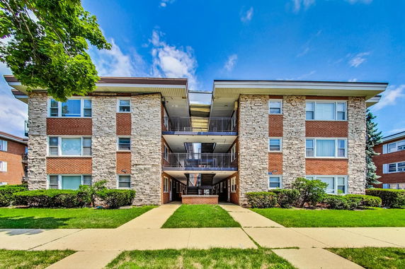 Front view of a multi-story apartment building with brick and stone facade.