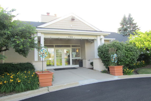Front view of a building with a small entrance porch and decorative plants.