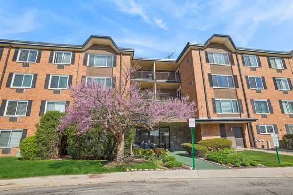Front view of a multi-story brick apartment building with balconies.