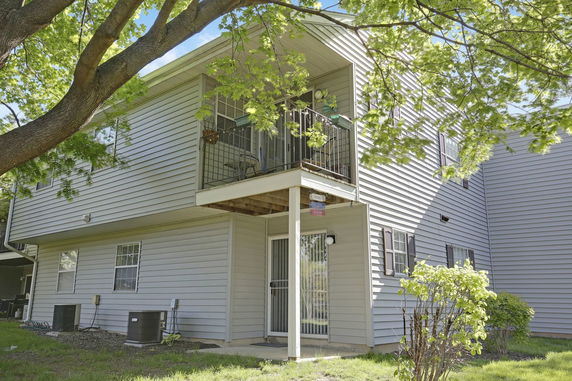 Front view of a two-story house with a balcony and glass door entrance.