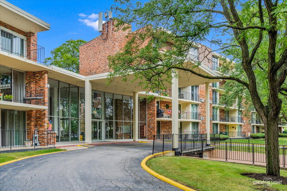 Front view of a multi-story brick building with large glass windows.