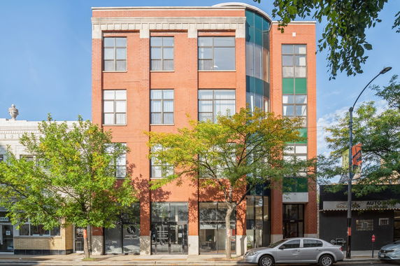 Front view of a multi-story brick building with large windows.
