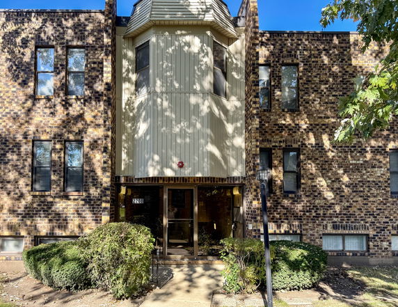 Front view of a brick apartment building with multiple windows.