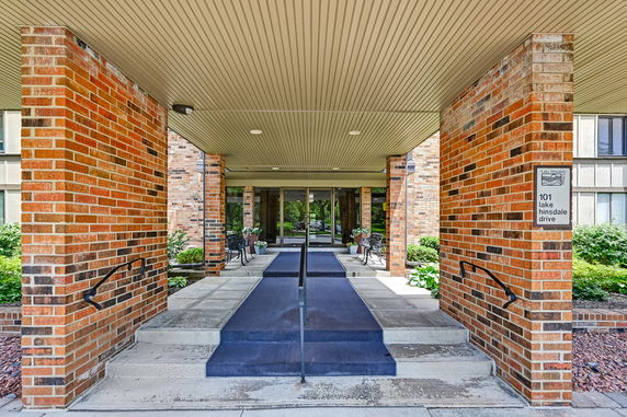 Front view of a building entrance with brick columns and blue carpeted ramp.