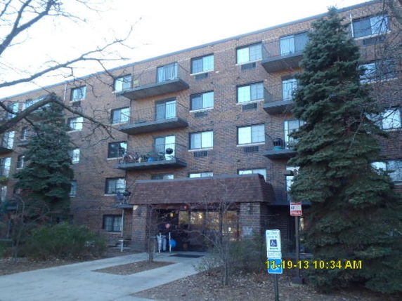 Front view of a multi-story brick apartment building with balconies.