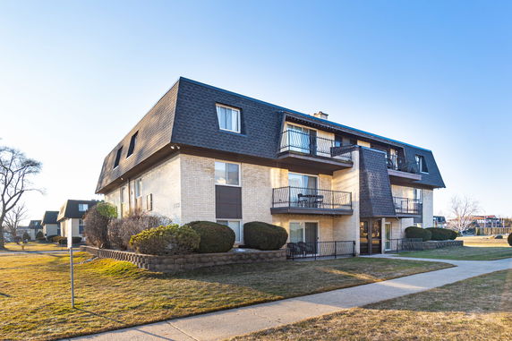 Front view of a multi-story residential building with balconies and pitched roof.