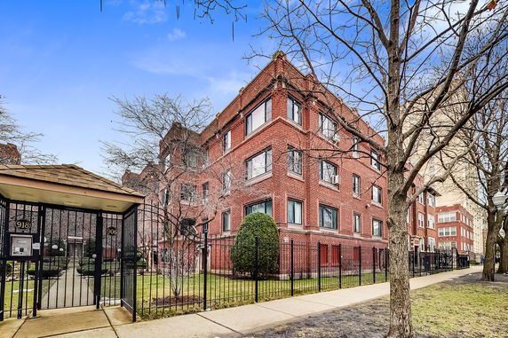 Front view of a multi-story brick building with large windows and a gated entrance.