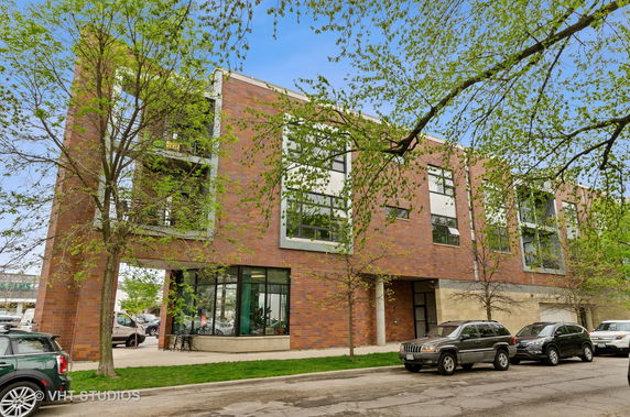 Front view of a modern three-story building with large windows and brick exterior.
