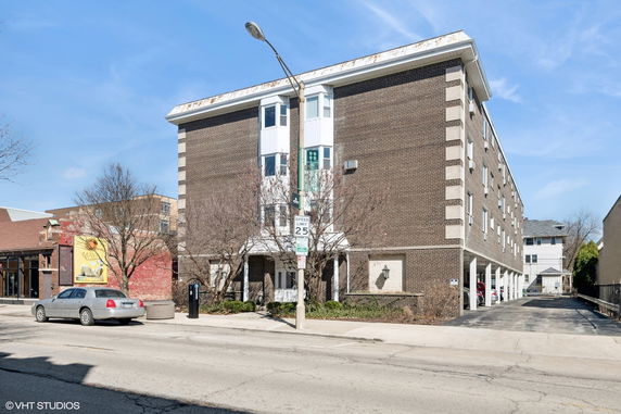 Front view of a multi-story apartment building with a brick exterior and bay windows.