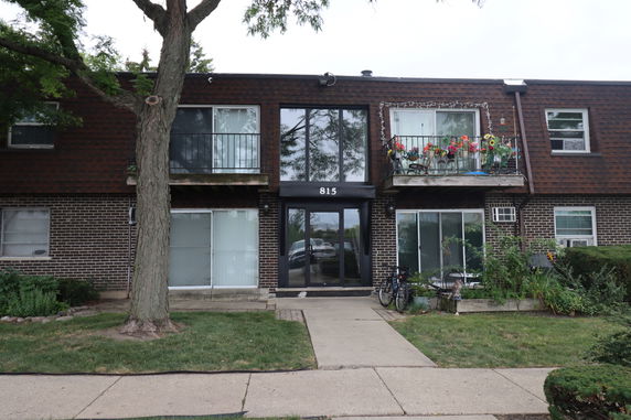Front view of a two-story brick apartment building with balconies and a central entrance.