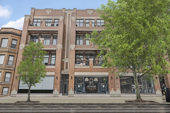 Front view of a multi-story brick building with retail space on the ground floor.