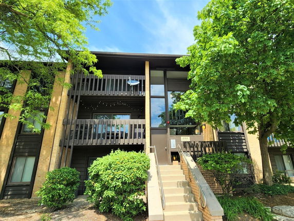 Front view of a two-story building with balconies and surrounding trees.