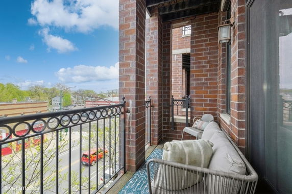 View from a balcony with brick walls overlooking a street and buildings.
