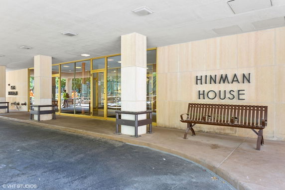 Front view of a building entrance with glass doors and a bench outside.