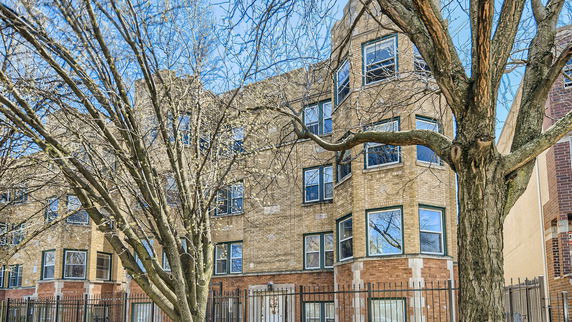 Front view of a multi-story brick apartment building with multiple windows.