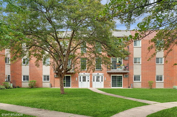 Front view of a three-story brick apartment building with white doors and multiple windows.