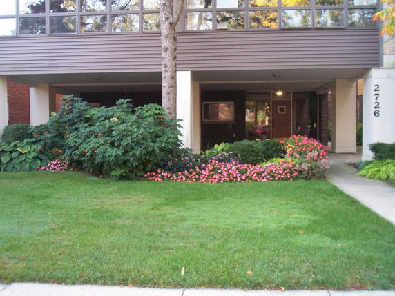 Front view of a multi-story building with a garden at the entrance.