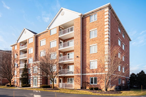 Front view of a multi-story brick apartment building with balconies.