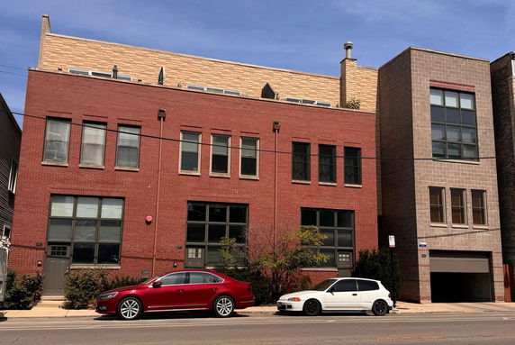 Front view of a two-story brick building with multiple windows and a garage.
