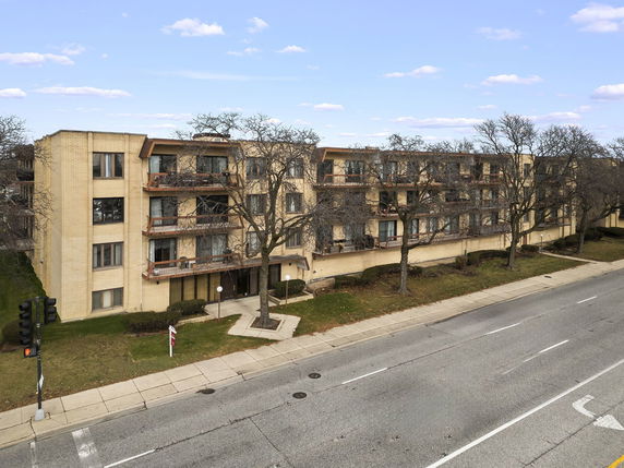 Front view of a multi-story apartment building along a street.
