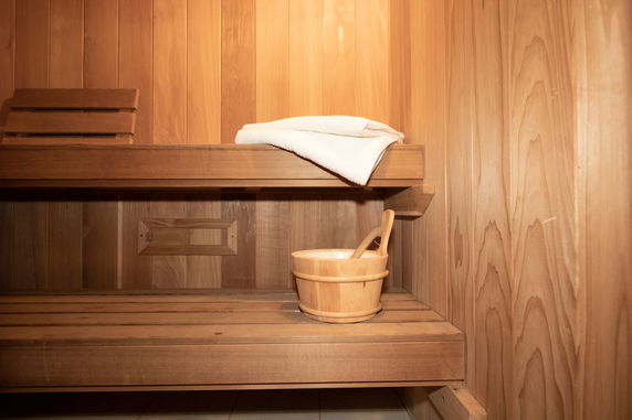 Interior of a wooden sauna with benches and a towel on the top bench.