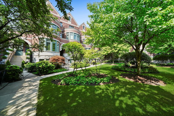 Front view of a multi-story brick house with large windows and landscaped garden.