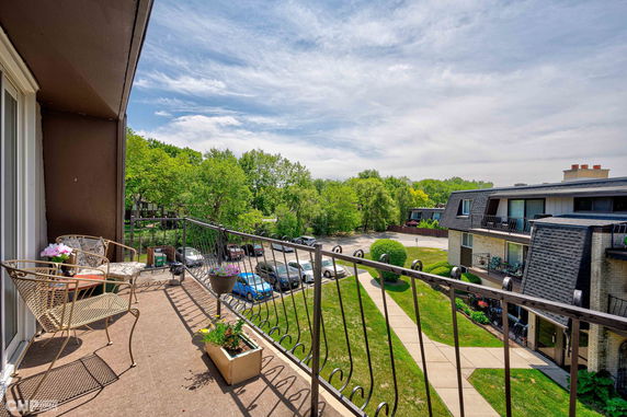 View from a balcony overlooking parking area and nearby residential buildings.