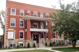 Front view of a three-story brick building with multiple windows and a covered entrance.