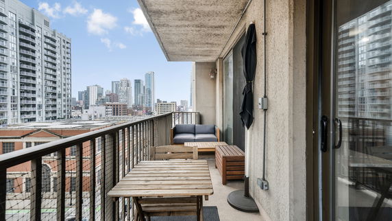Balcony view of cityscape with high-rise buildings and outdoor furniture.