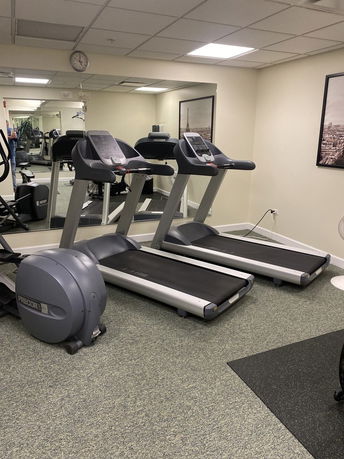 Room with exercise equipment including treadmills and mirrored wall.