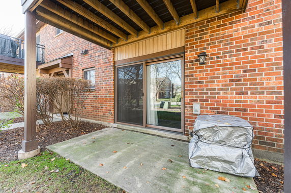 Brick exterior of a house with a sliding glass door and a covered outdoor air conditioning unit.