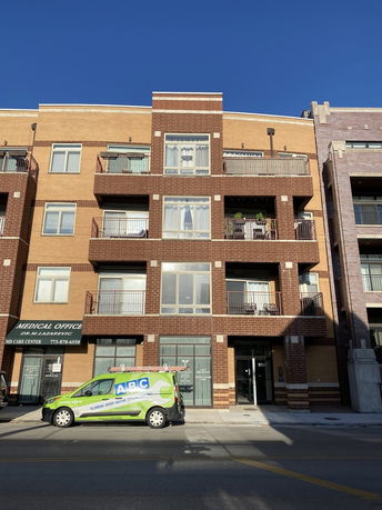 Front view of a multi-story building with balconies and a medical office on the ground floor.