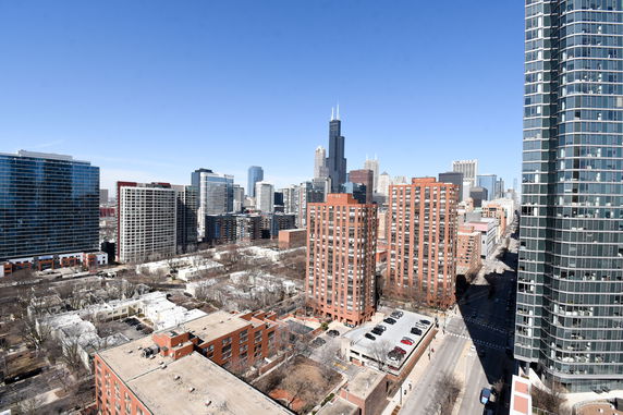 Wide panoramic view of a city's skyline with various skyscrapers and buildings under a clear blue sky.