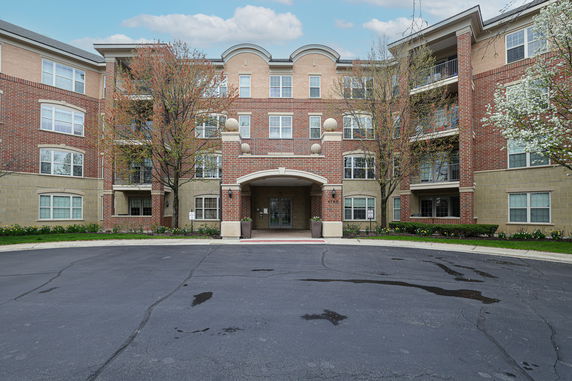 Front view of a multi-story residential building with brick exterior and arched entrance.