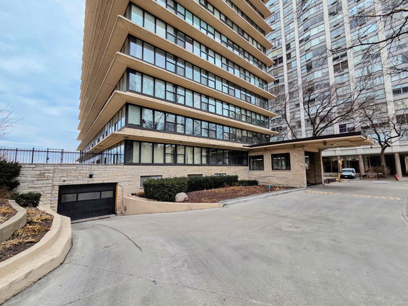 Front view of a multistory building with large windows and a parking garage entrance.