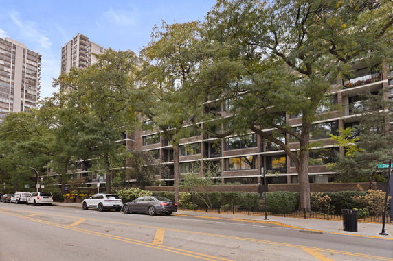Front view of a mid-rise building with multiple balconies and large windows.