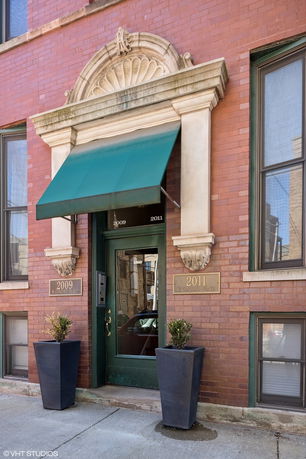 Front view of a brick building entrance with decorative arch and green awning.