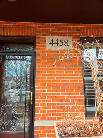Front view of a brick house with a decorative glass door and house number 4458.
