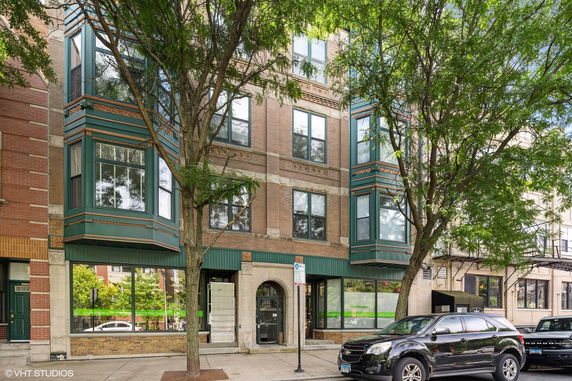 Front view of a multi-story building with large windows and a green awning.