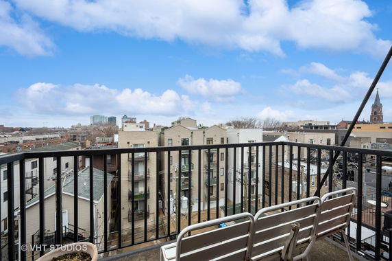 Balcony view overlooking rooftops and buildings in a cityscape.
