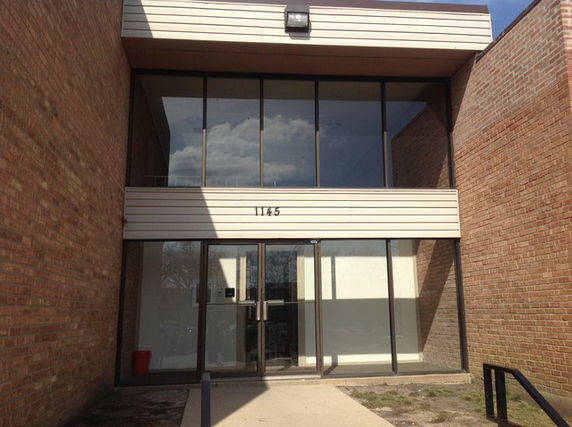 Front view of a building with large glass windows and a flat roof.