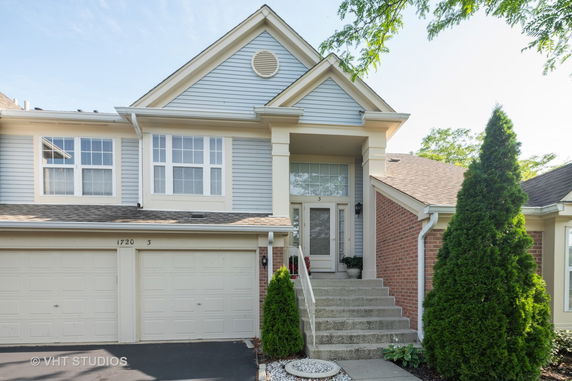 Front view of a two-story house with double garage and front steps leading to the entrance.