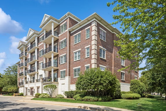 Front view of a multi-story apartment building with balconies and brick exterior.