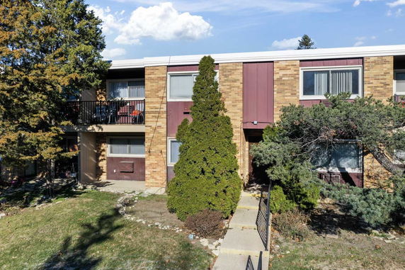 Front view of a two-story brick building with a balcony and walkway.