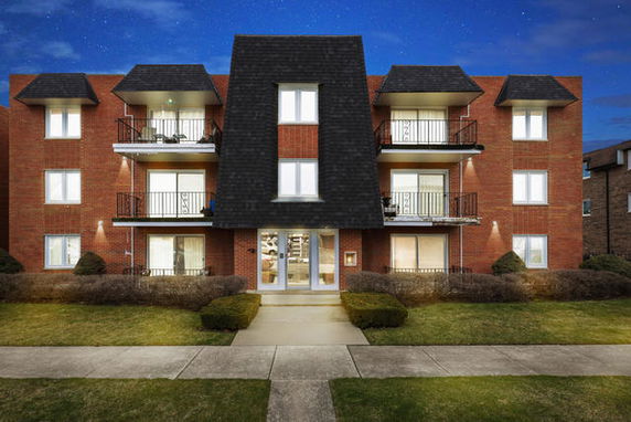 Front view of a multi-story brick apartment building with balconies.