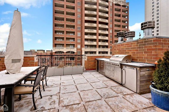 Rooftop view with outdoor kitchen featuring a grill and seating area.