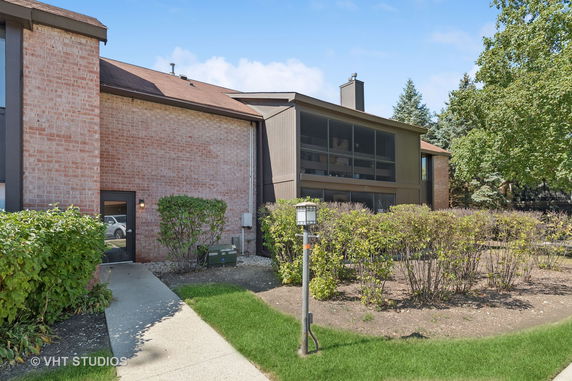 Front view of a two-story brick building with a sloped roof and large windows.