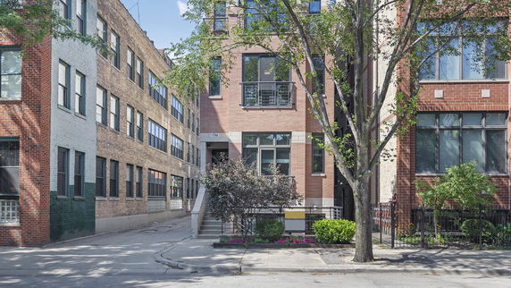 Front view of a multi-story brick building with large windows.